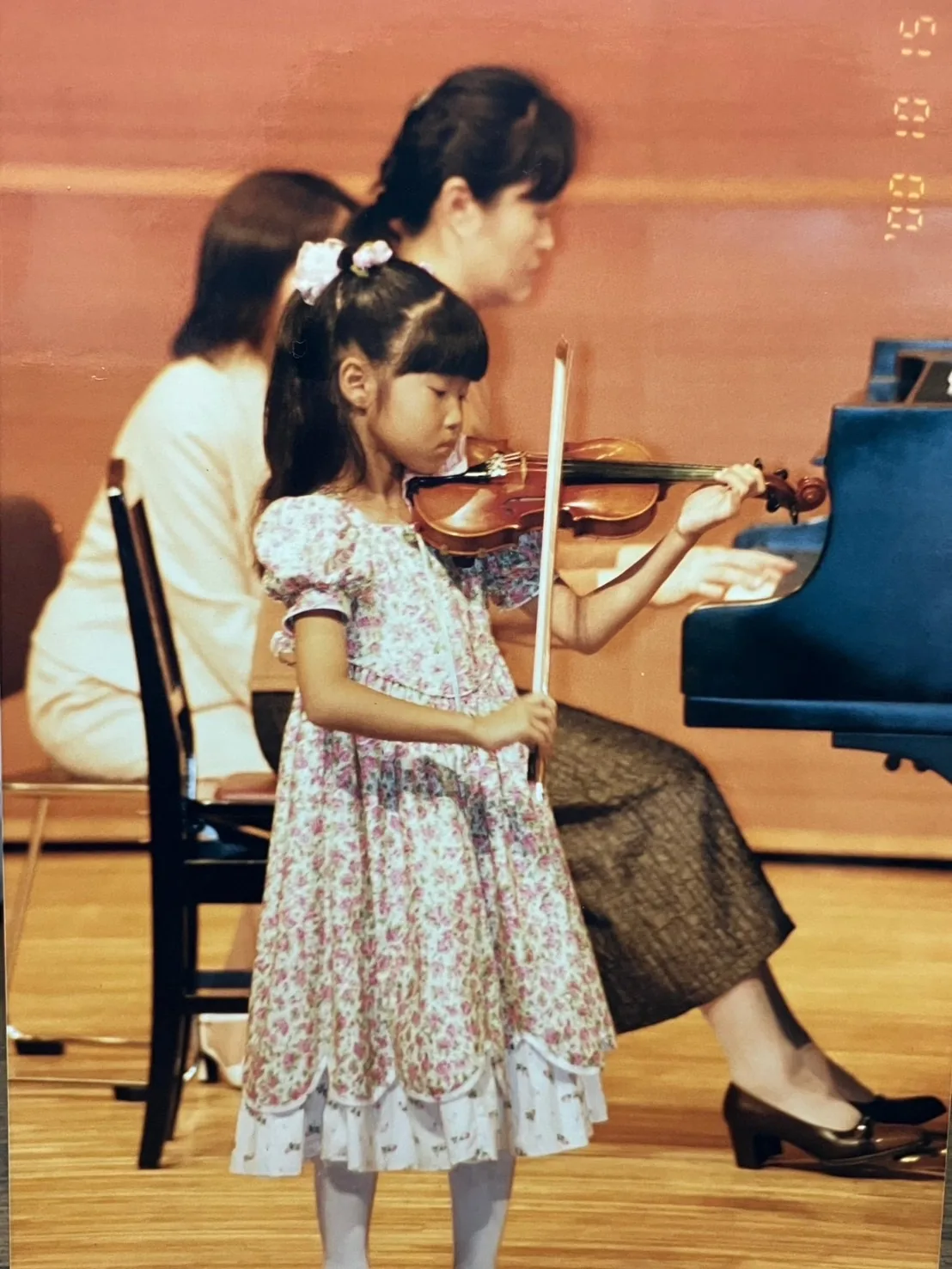 発表会でヴァイオリンを演奏する子どもと見守る講師